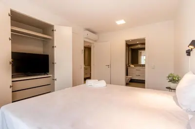 a white bedroom with a large bed and a flat screen tv at The Albufeira Concierge - Amazing Pool & Sunshine in Albufeira