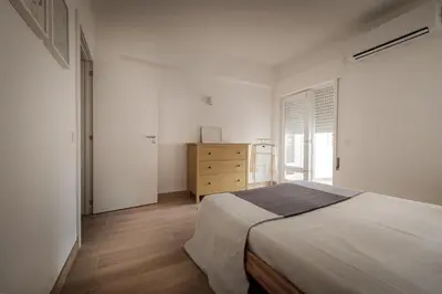 a white bedroom with a bed and a dresser at Sunny Days beach apartment in Quarteira