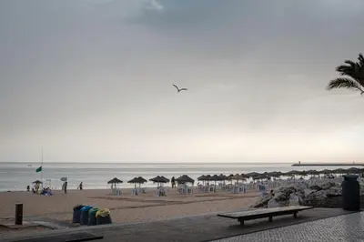 a beach with umbrellas and people on the beach at Sunny Days beach apartment in Quarteira