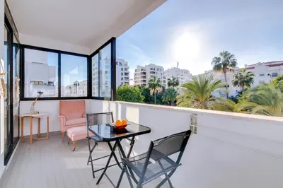a balcony with a table and chairs and windows at Apartamento Estrela do Mar in Quarteira
