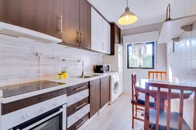 a kitchen with wooden cabinets and a table with a dining room at Apartamento Estrela do Mar in Quarteira
