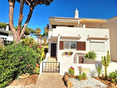 a white house with a palm tree and plants at Seaside SunFlower in Quinta do Lago