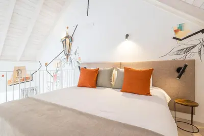 a bedroom with a bed with orange and gray pillows at LODO Suites Arco - Mezanino apartment by HD in Faro