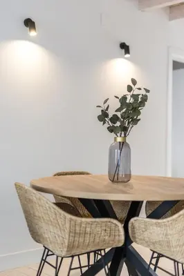 a dining room table with chairs and a vase of flowers at LODO Suites Arco - Mezanino apartment by HD in Faro