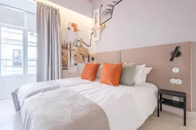 a bedroom with a large white bed with orange pillows at LODO Suites Ala - Studio mezanino by HD in Faro