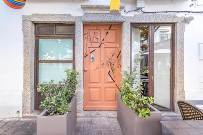 an orange door on a building with potted plants at LODO Suites Se - Mezanino room by HD in Faro