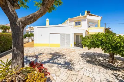 a white house with a tree in front of it at Villa Brejos in Albufeira
