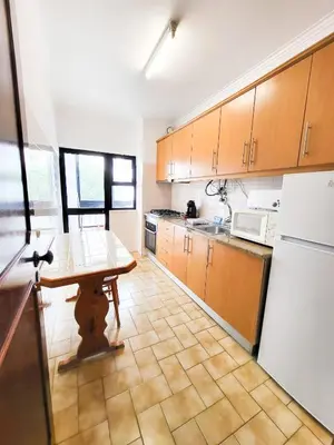 a kitchen with a wooden table and a refrigerator at T1 Largo Frente - Familiar in Quarteira