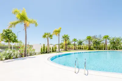 a swimming pool with palm trees in the background at Lakes 24 at Praia da Falesia Vilamoura in Vilamoura