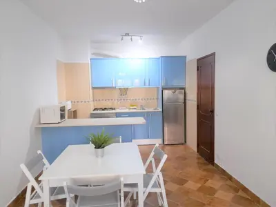 a kitchen with blue cabinets and a white table and chairs at T1 MIRA PRAIA a in Quarteira