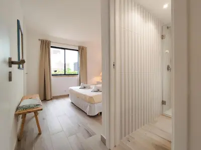 a white bedroom with a bed and a window at Solar dos Pinheiros in Vilamoura