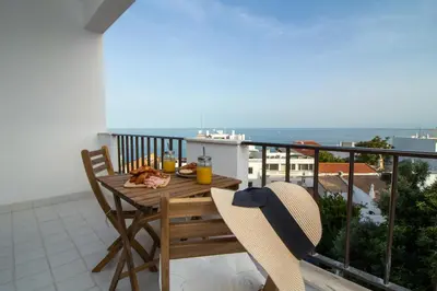 a wooden table and chairs on a balcony with the ocean at Old Town Apartment Panoramic NearThe Beach in Albufeira