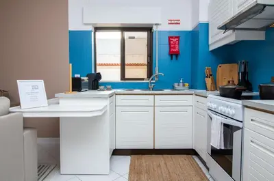 a kitchen with white cabinets and a blue wall at Old Town Apartment Panoramic NearThe Beach in Albufeira