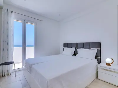 a white bedroom with a large bed and a large window at AL - Atlântida Penthouse in Quarteira
