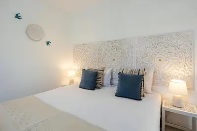 a bedroom with a large white bed with blue pillows at Coral Boutique Suites in Albufeira