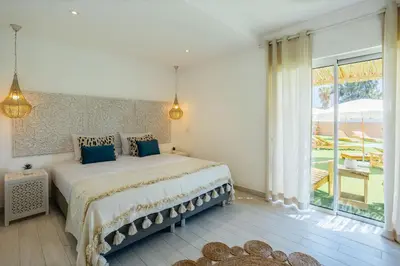 a bedroom with a large bed and a large window at Coral Boutique Suites in Albufeira