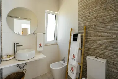 a bathroom with a sink and a toilet and a mirror at Coral Boutique Suites in Albufeira
