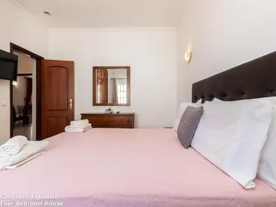 a bedroom with a large bed with pink sheets and a mirror at Akisol Albufeira Sun in Albufeira