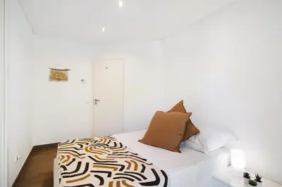 a white bedroom with a bed with a black and white blanket at Pine Lodge in Vilamoura