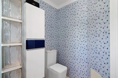 a bathroom with a toilet and a blue tiled wall at Pine Lodge in Vilamoura