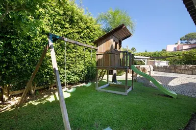 a playground with a slide and a swing at Pine Lodge in Vilamoura