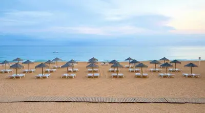 a group of chairs and umbrellas on a beach at Votre refuge en bord de mer ! in Albufeira
