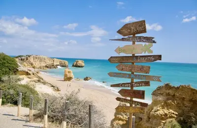 a directional sign on a beach with the ocean at Votre refuge en bord de mer ! in Albufeira