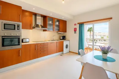 a kitchen with wooden cabinets and a table and a dining room at Votre refuge en bord de mer ! in Albufeira