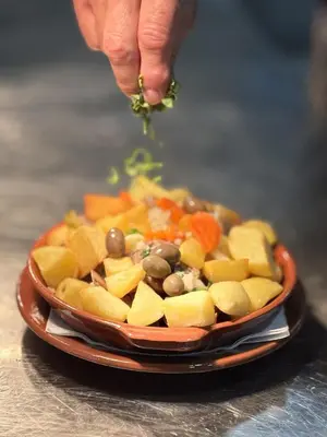 a person holding a piece of food in a bowl of vegetables at Albufeira Central 6 by Homing in Albufeira