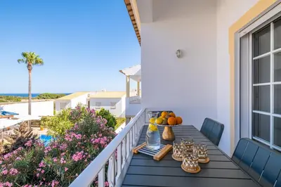 a table on a balcony with food and a view of the ocean at Martina Apartment - SeaView in Albufeira