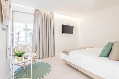 a white bedroom with a bed and a table at LODO Suites Ria - Private Room by HD in Faro