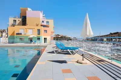 a swimming pool with a blue chair and an umbrella at Apartamento W Marina by Sunnyway in Albufeira