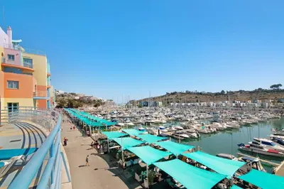 a marina with blue umbrellas and boats in the water at Apartamento W Marina by Sunnyway in Albufeira