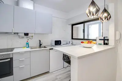 a white kitchen with a bowl of fruit on a counter at Renovated Oasis Ocean View 1BD Wi-Fi Beach 3 min in Albufeira