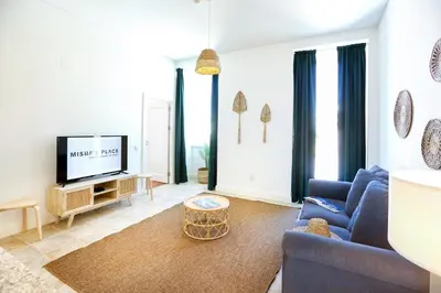 a living room with a blue couch and a tv at Lovely Faro Apartment in Faro