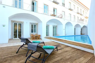 a patio with two chairs and a swimming pool at Ria Formosa Vista Duplex Charm in downtown Faro in Faro