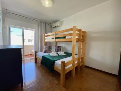 a bedroom with a bunk bed with a green table at Quarteira Beach Apartment by Homing in Quarteira