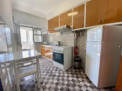 a kitchen with a white refrigerator and a table at Quarteira Beach Apartment by Homing in Quarteira