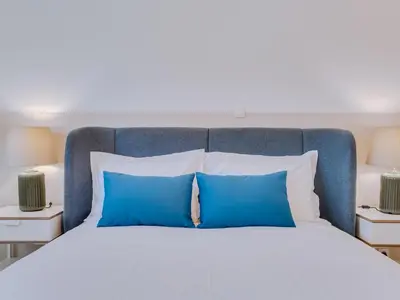 a bed with blue and white pillows and two lamps at AL - Apartamento Montemar in Vilamoura