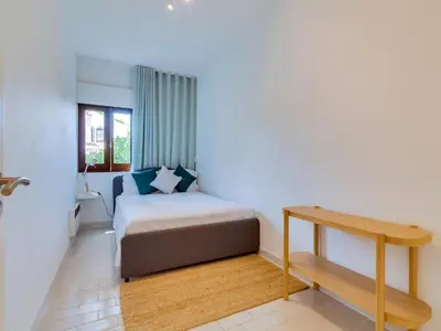 a small bedroom with a bed and a table at AL - Apartamento Montemar in Vilamoura