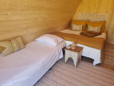 two beds in a wooden room with a table at Eco Cabin - Villa das Alfarrobas in Algoz