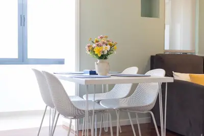 a white table with chairs and a vase of flowers at Mercado Apartments in Faro