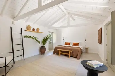 a white room with a bed and a table at Âmago Guesthouse in Santa Bárbara de Nexe