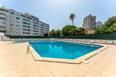 a large swimming pool with chairs and a building at Modern 2 BDR Flat W/Balcony and Pool by LovelyStay in Albufeira
