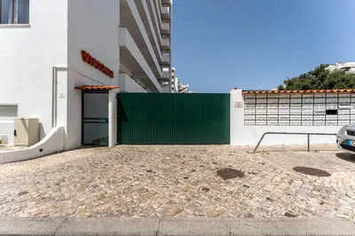 a green gate on a building with a parking lot at Modern 2 BDR Flat W/Balcony and Pool by LovelyStay in Albufeira
