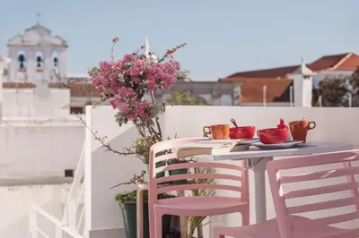 a table and chairs on a balcony with flowers at Sunlight House in Faro