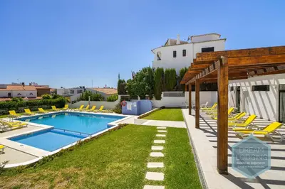 a swimming pool with yellow lounge chairs in a yard at Palm Tree - Dream Lodging in Albufeira
