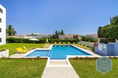 a swimming pool with yellow chairs in a yard at Palm Tree - Dream Lodging in Albufeira