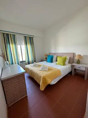 a bedroom with a large bed with yellow and blue pillows at Residence Golf-Vilamoura! in Quarteira