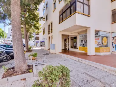 a white building with a tree in front of it at AL - Apartamento Moural in Quarteira